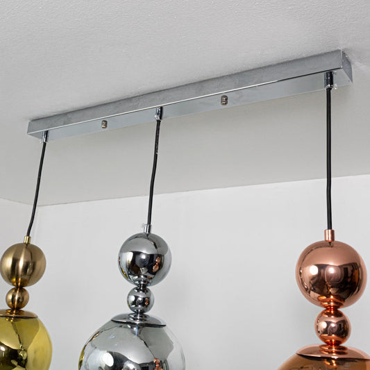 Close view of metallic pendant lights showing reflective gold silver and copper sculpted shapes highlighting their bold contemporary lighting style.