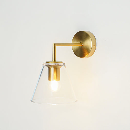 Contemporary brass wall light with clear glass shade creating warm elegant interior lighting decor.