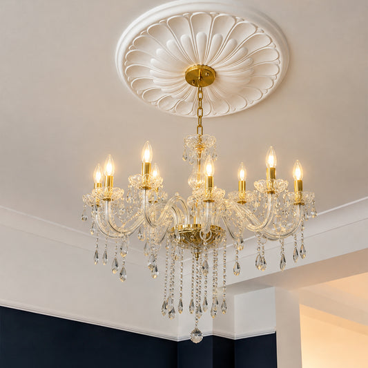 A multi-light crystal chandelier with gold-toned metal arms and hanging clear glass teardrop pendants, suspended from a decorative white ceiling medallion in an interior room.