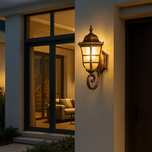 Gold metal outdoor wall lantern light on with frosted glass panels creating warm welcoming illumination for a modern home entrance porch patio and pathway Decor.