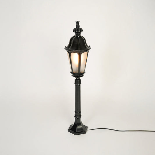 Vintage style black metal garden lamp post with clear glass panels on neutral background perfect for outdoor lawn or driveway lighting.