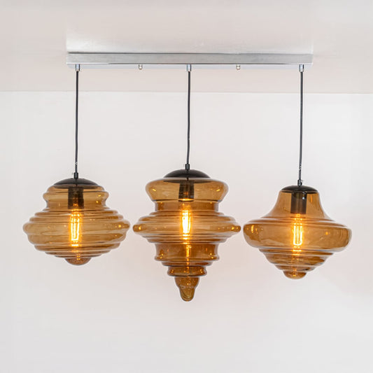 Amber ribbed glass pendant lights with black metal accents for stylish dining room decor.