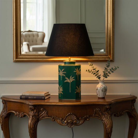 Green ceramic bedside table lamp with black fabric shade placed on wooden console for warm ambient home lighting.