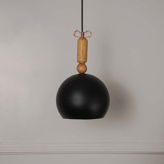 Black dome pendant light with wooden holder and hanging cord placed against neutral wall background enhancing bold modern lighting decor styling.