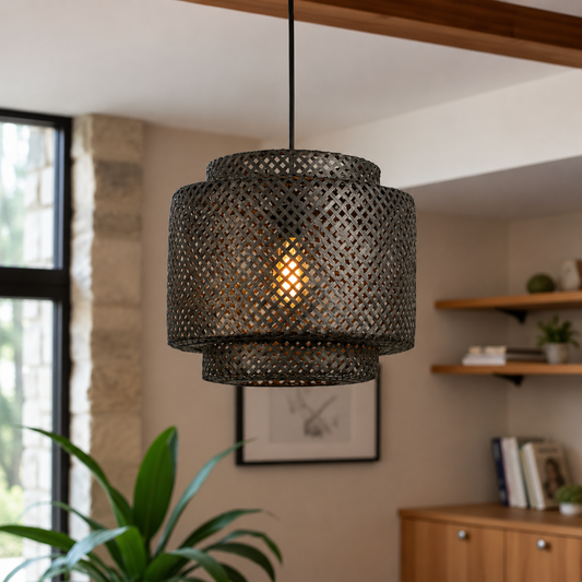 A dark metal pendant light with a cylindrical, open-lattice shade hangs in a warm, modern room setting with a wooden ceiling beam, shelves, and a plant in the background.