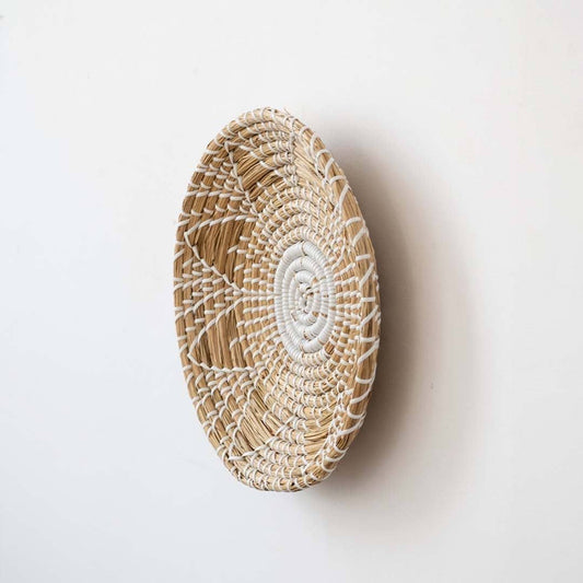 Handwoven seagrass round wall basket decor in natural beige with white spiral woven profile displayed from side on white.