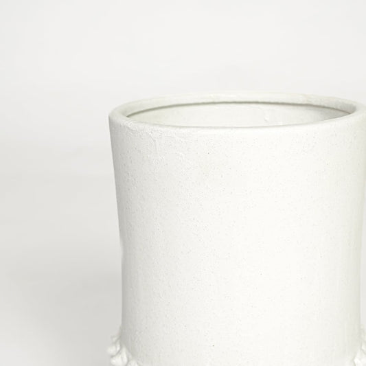 Detailed closeup of ceramic flower vase with raised textured pattern and solid tripod base in white finish.