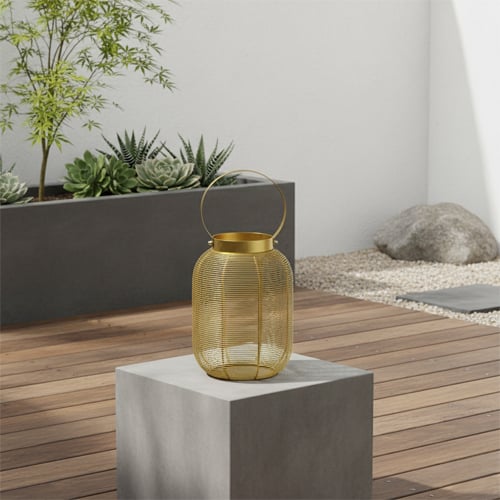 Outdoor garden lantern with warm glow on wooden table creating cozy ambiance for seasonal decor styling.