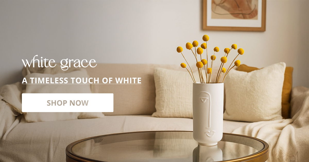 White flower vase styled on coffee table with floral stems creating timeless clean and modern decor look.