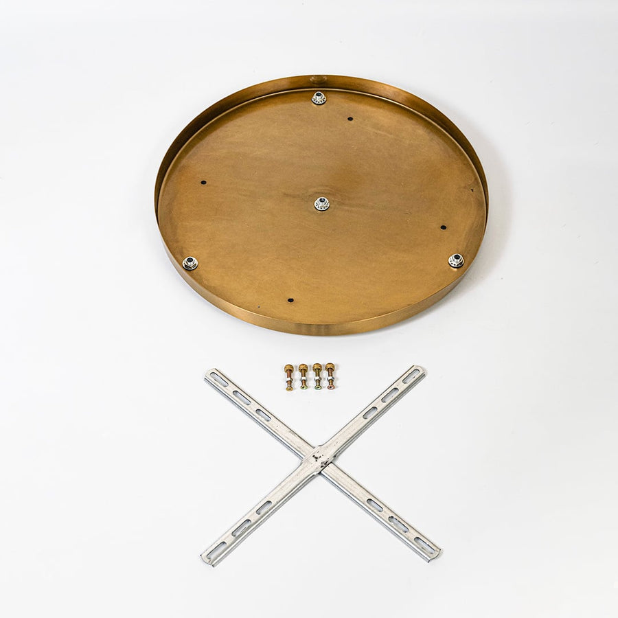 Round metal ceiling plate in warm gold finish shown with cross mounting bracket screws and hardware laid out on white background.