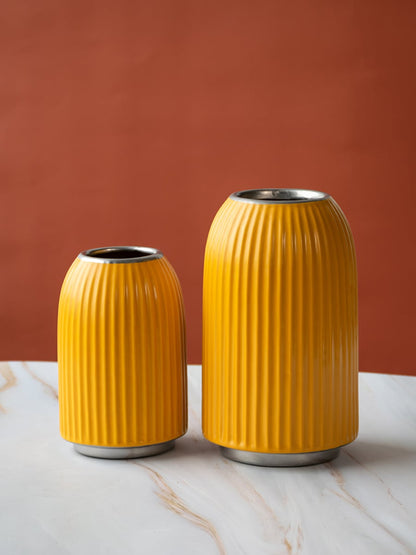 A yellow ribbed vase shown with additional decor elements in a grouped arrangement emphasizing its modern shape and vibrant appeal.