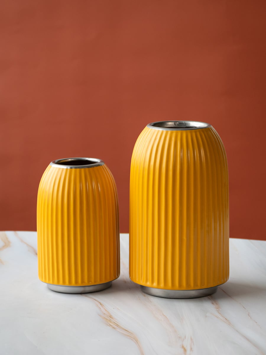 A yellow ribbed vase shown with additional decor elements in a grouped arrangement emphasizing its modern shape and vibrant appeal.