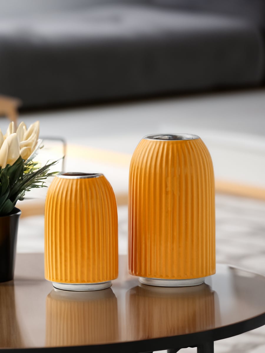 A stylish yellow ribbed vase featured in a grouped lifestyle setup highlighting its bold color and modern textured design in home decor.