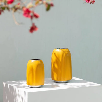 A bright yellow ribbed vase displayed in a clean minimal setting adding a vibrant modern accent to contemporary home decor styling.