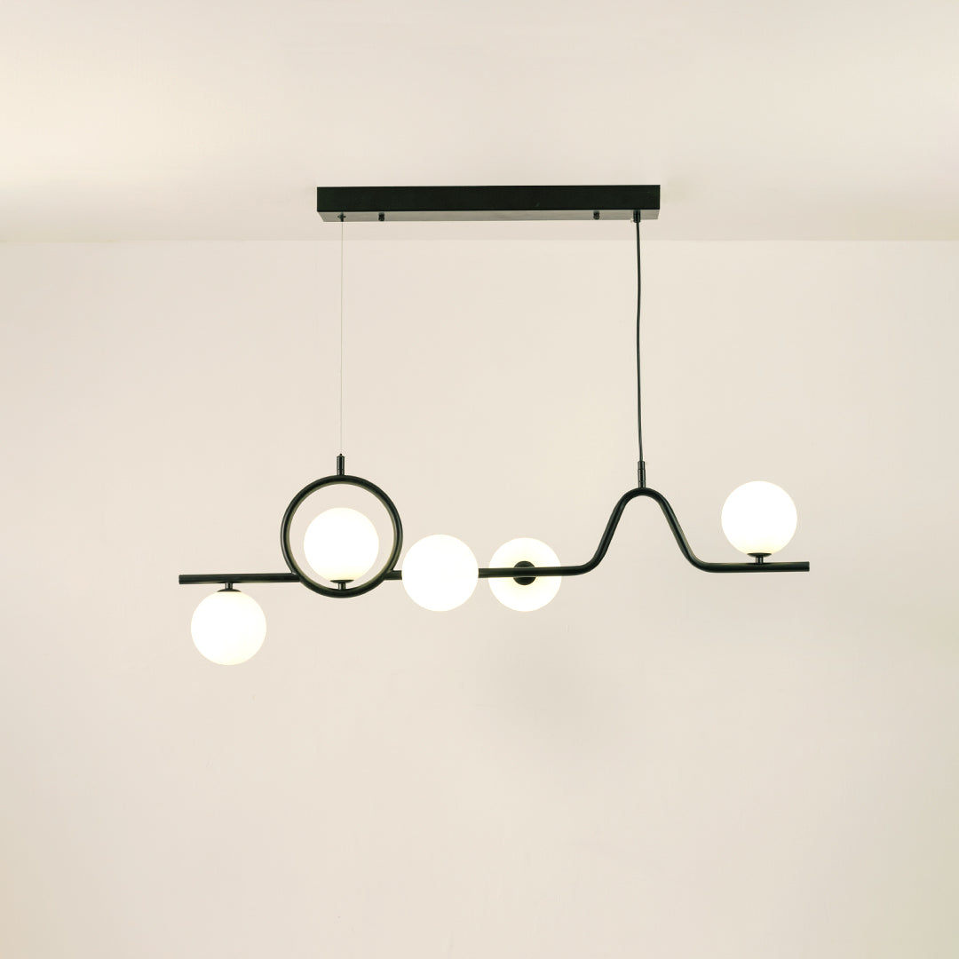 Black metal chandelier with frosted glass globe shades creating warm ambient lighting for modern dining room interiors.
