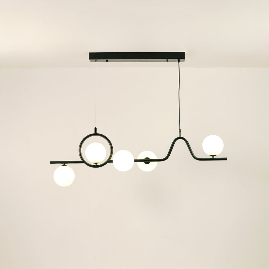 Black metal chandelier with frosted glass globe shades creating warm ambient lighting for modern dining room interiors.