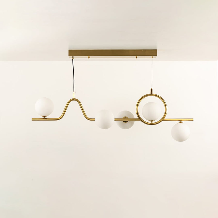 Gold chandelier with circular accent and white globe bulbs in a front view against a plain background with lights on perfect for artistic lighting décor.