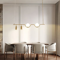 Gold metal linear chandelier with frosted globes and spotlights styled in a modern interior adding warm ambient lighting.