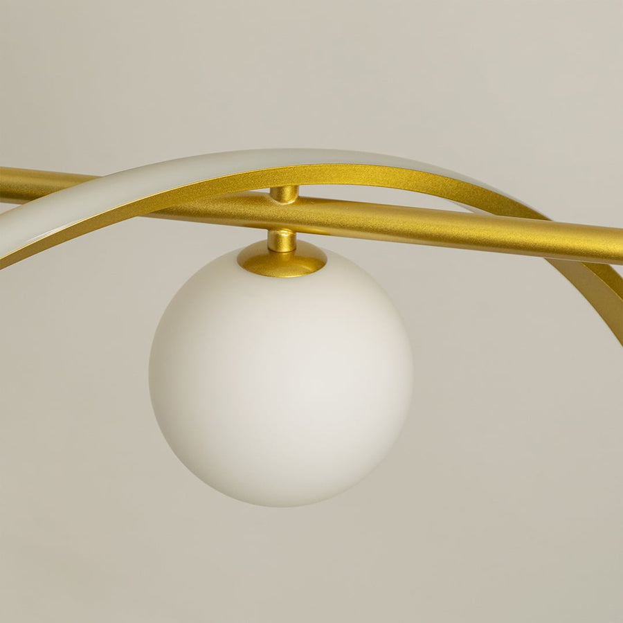 Detailed closeup of gold wave chandelier highlighting curved metal design and soft matte white globes for modern interiors.