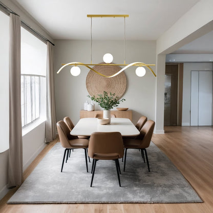 Modern gold metal wave chandelier with white globes styled in a warm living room setting for elegant ceiling lighting decor.