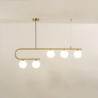 Gold asymmetrical ceiling light with curved arm and white globes in a front view against a plain background with lights on perfect for luxury lighting décor.