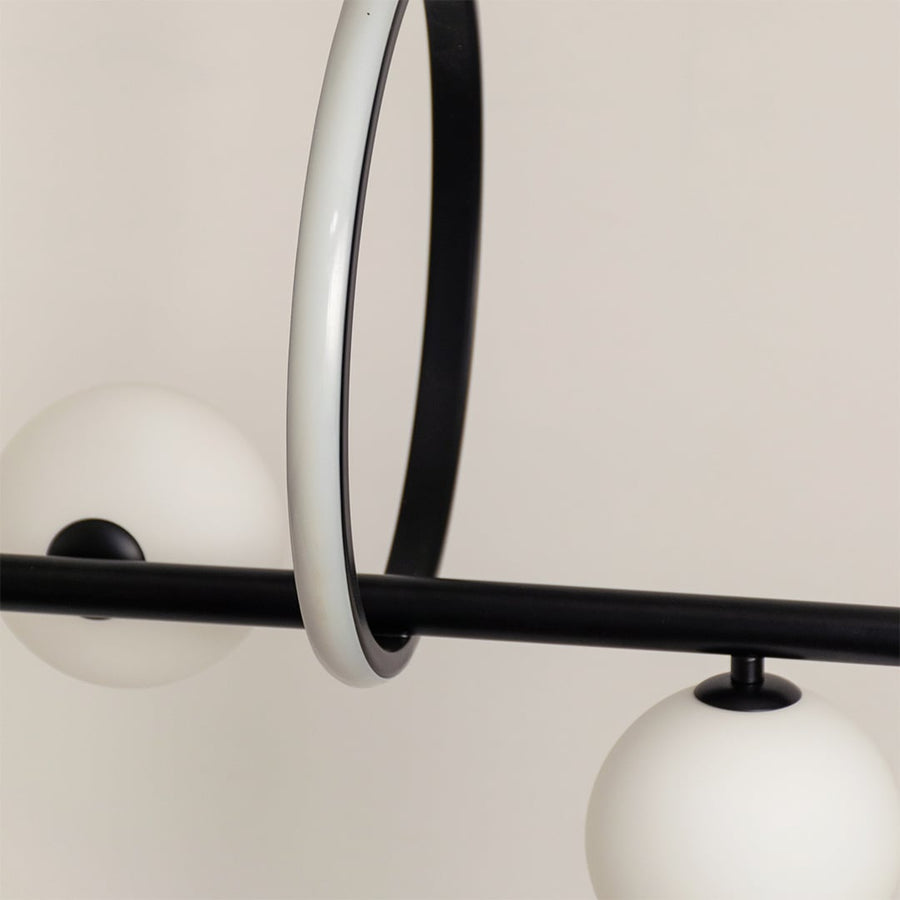 Detailed closeup of black metal chandelier showing round frosted spheres curved frame and modern ring accent.