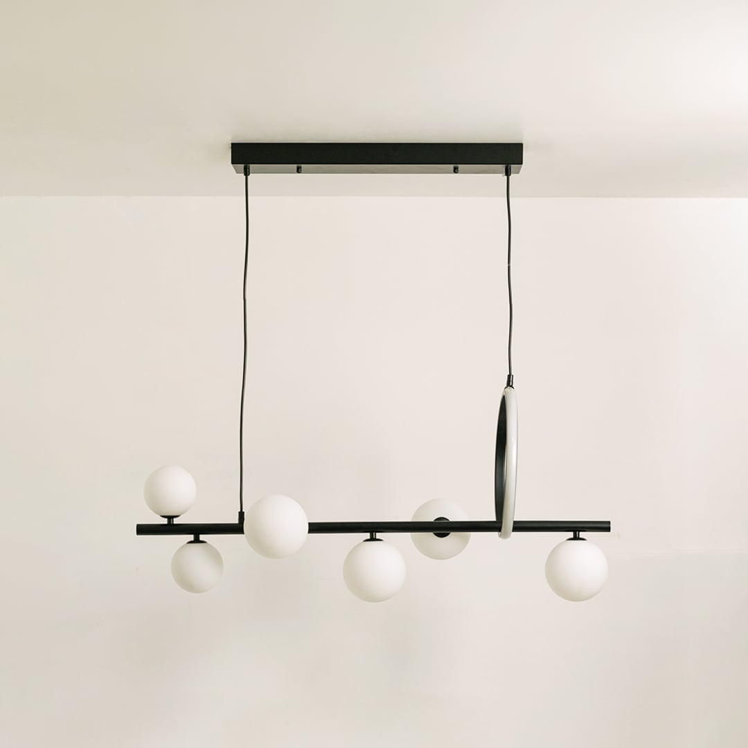 Black metal chandelier on a white background with the lights off highlighting its sculptural minimal silhouette.