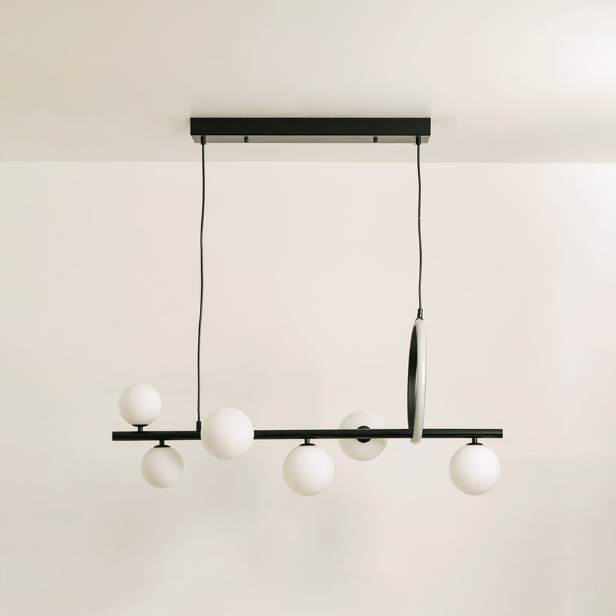 Black metal chandelier on a white background with the lights off highlighting its sculptural minimal silhouette.