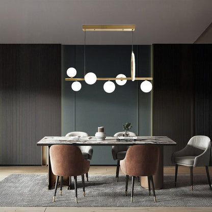 Gold metal chandelier with frosted glass globes styled in a modern interior adding warm elegant ambient lighting to the space.