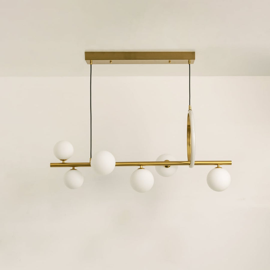 Gold metal chandelier on a white background with lights off highlighting its sculptural modern silhouette.