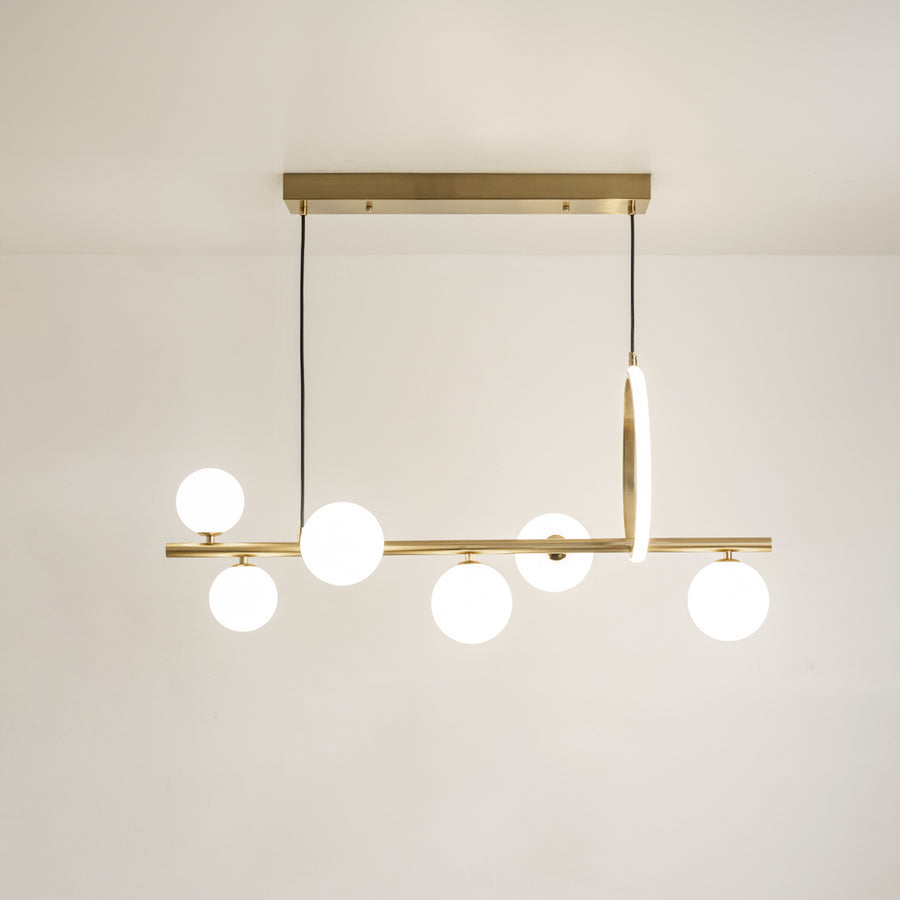 Gold metal chandelier with frosted glass globe shades and vertical LED accent creating elegant modern ceiling lighting.