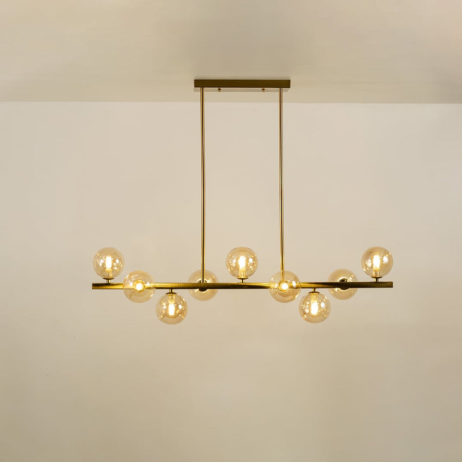 Gold multi arm chandelier with globe bulbs in a front view against a plain background with lights on ideal for luxury décor and premium home lighting.