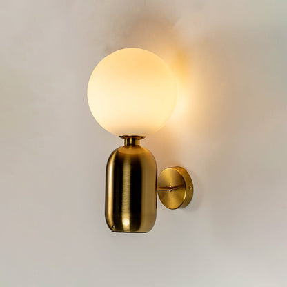 Luxury brass wall sconce with frosted glass globe shade glowing warm light white background for bedroom hallway and modern home decor.
