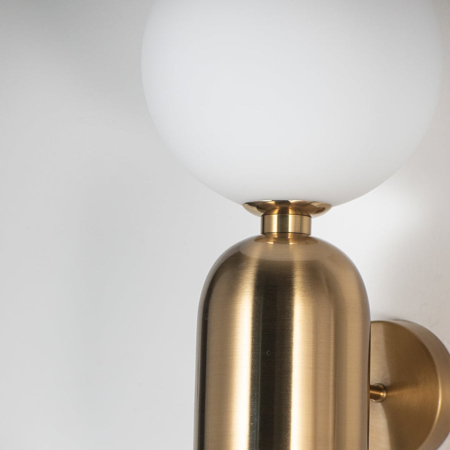 Detailed closeup view of brass wall sconce with frosted white glass shade premium indoor wall lighting for bedroom and hallway decor.