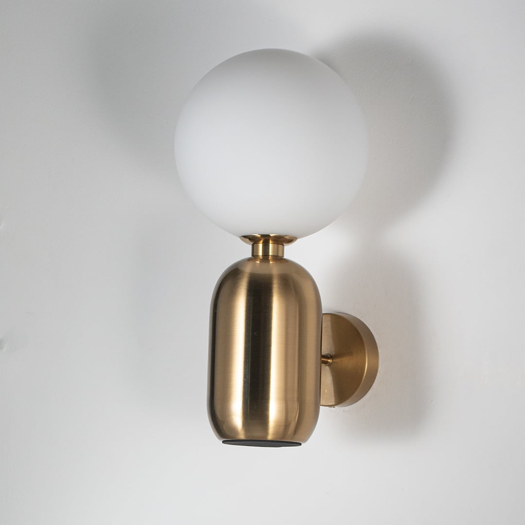 Modern brass wall sconce with frosted white glass globe shade light off white background for living room bedroom and hallway lighting.