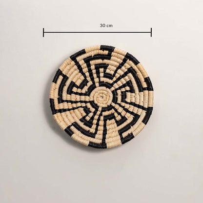A handwoven natural and black rattan wall decor plate displayed on a white background clearly showing a diameter of 30 cm for accurate wall decor measurement.