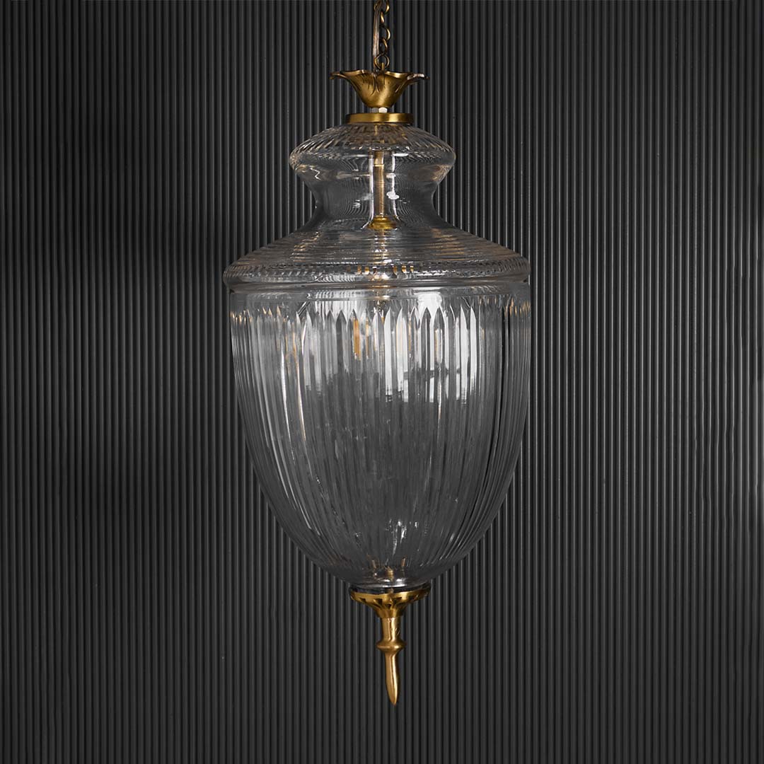 Clear glass lantern pendant light with brass accents glowing for luxurious ambient lighting.