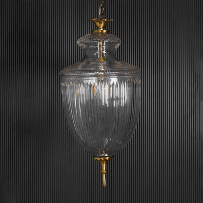 Clear glass lantern pendant light with brass accents glowing for luxurious ambient lighting.