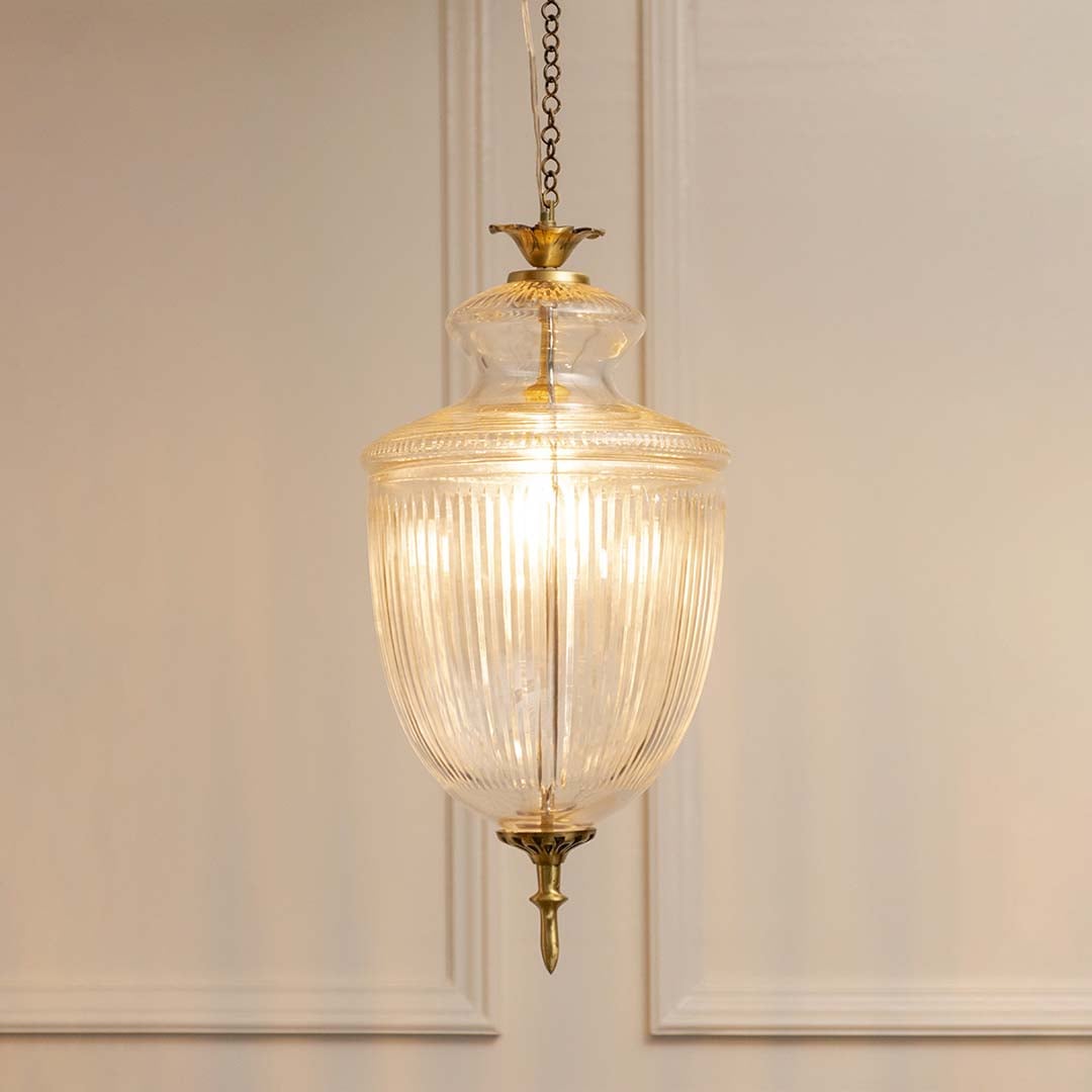 Antique brass and ribbed glass lantern pendant light with warm glow for refined home decor spaces.