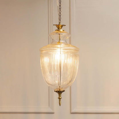 Antique brass and ribbed glass lantern pendant light with warm glow for refined home decor spaces.