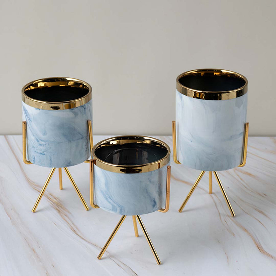 Set of three white marble finish metal planter pots with gold stands for elegant tabletop styling and home decor.