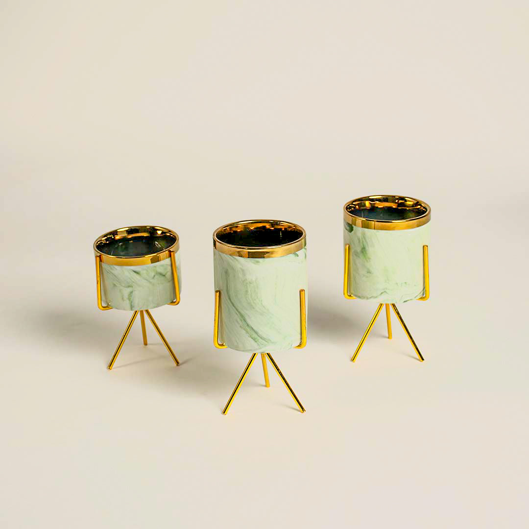 Set of three mint green marble texture cylindrical planters resting on matching metallic gold tripod wire stand frames.