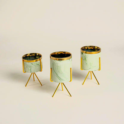 Set of three mint green marble texture cylindrical planters resting on matching metallic gold tripod wire stand frames.
