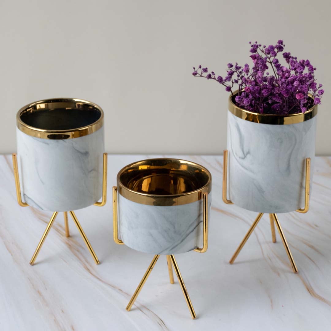 A marble planter with a gold stand shown in a styled lifestyle grouping adding a refined modern touch to contemporary home decor.
