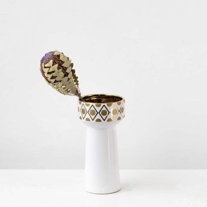 A sleek white vase with gold geometric accents shown in a bright lifestyle setup adding a modern decorative touch to interior spaces.