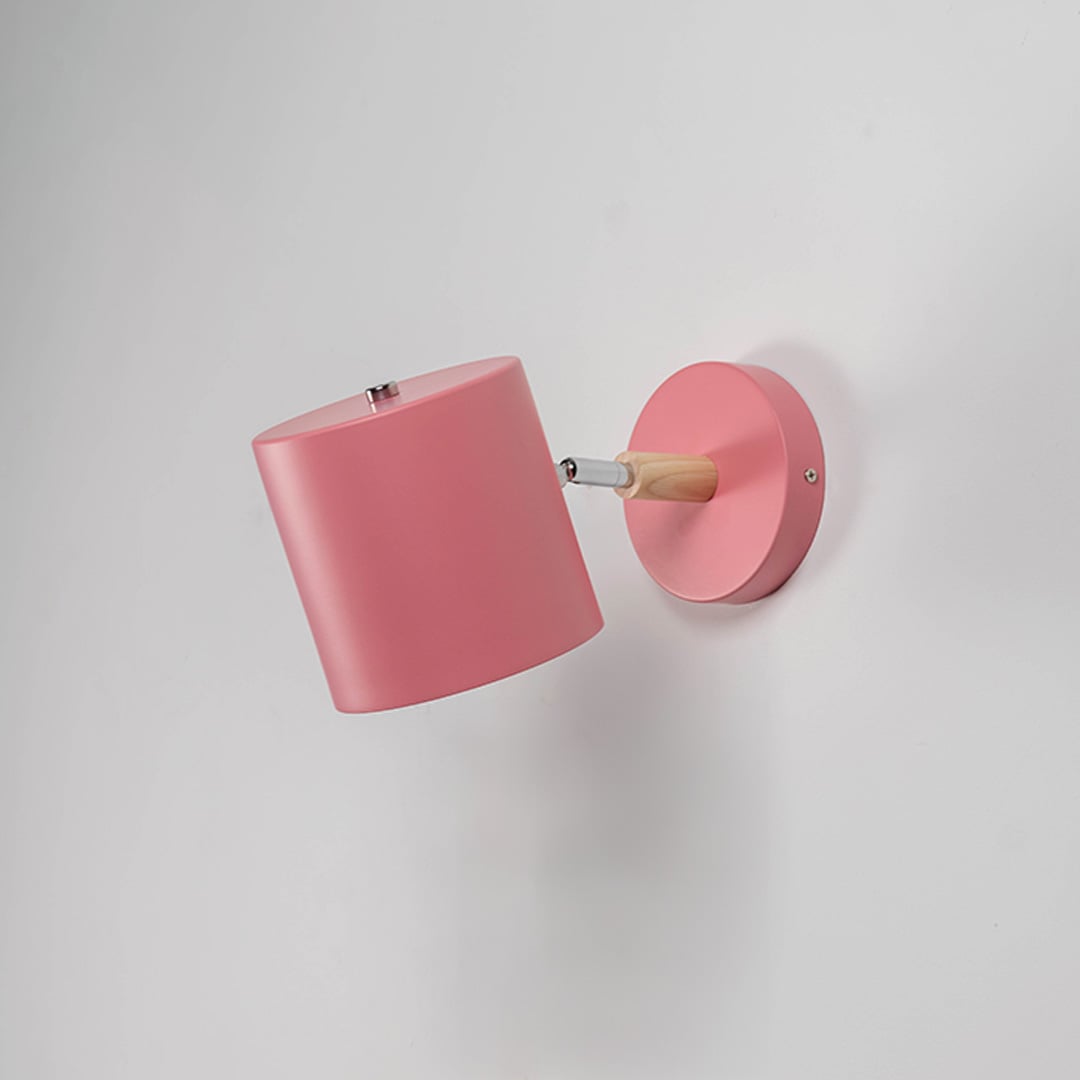 Muted pink wall lamp with wooden arm off against white wall highlighting its minimal modern appeal.