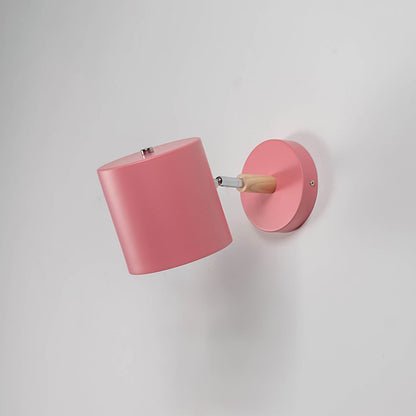Muted pink wall lamp with wooden arm off against white wall highlighting its minimal modern appeal.