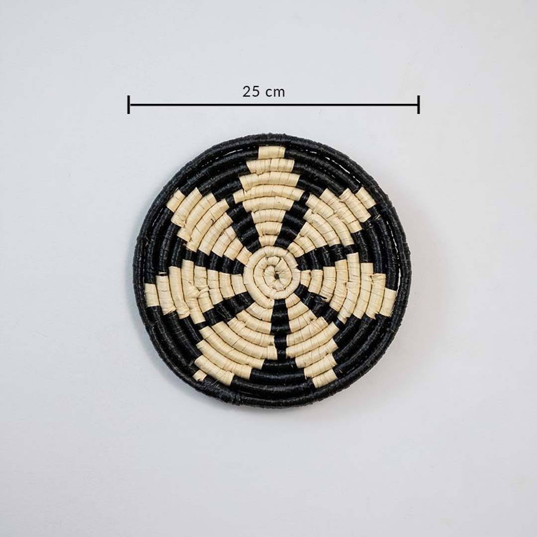 Round woven coaster with black and beige pattern on a white background, with a measurement label indicating 25 cm.