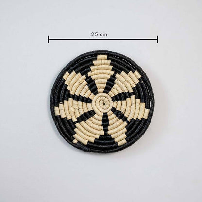 Round woven coaster with black and beige pattern on a white background, with a measurement label indicating 25 cm.