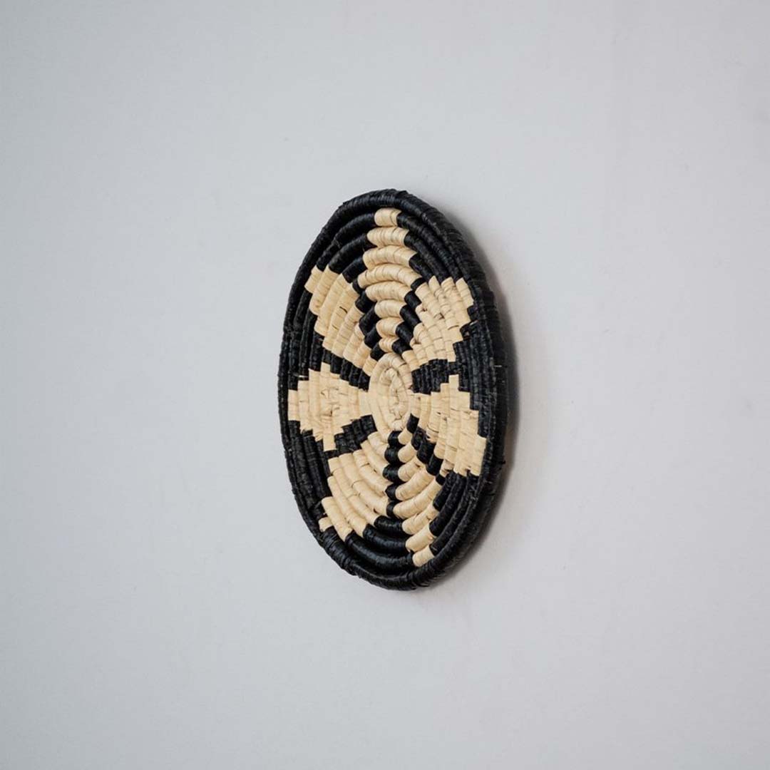 Side profile of handwoven bamboo wall plate in black beige tones highlighting crafted weave and natural texture.
